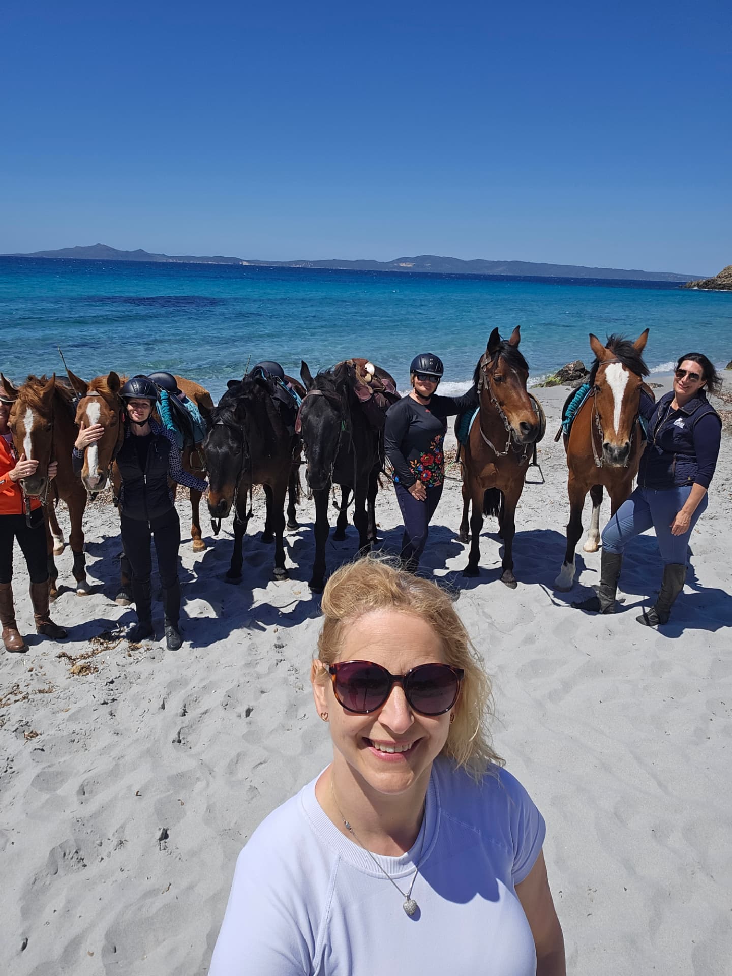Monika with a group of riders and horses on a Sardinian beach